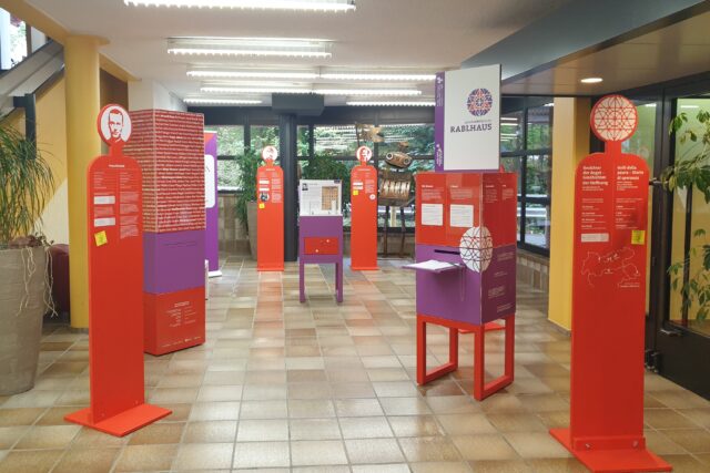Ausstellungselemente in Rot und Violett in einem gefliesten Raum