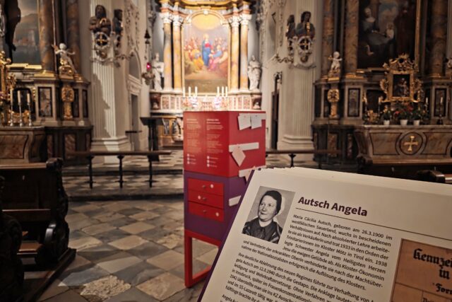 rot-violettes Ausstellungselement und Karteikarte mit Foto in Kirchenraum