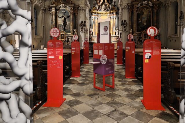 rot-violette Ausstellungselemente in einem Kirchenraum