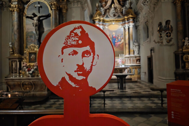 Porträt eines Soldaten auf roter Figur, im Hintergrund Kirchenraum