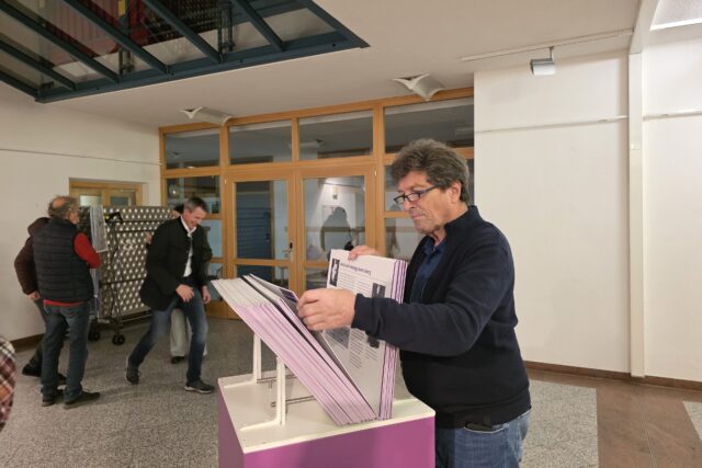 Mann mit Brille durchblättert die Biographiekartei der Ausstellung