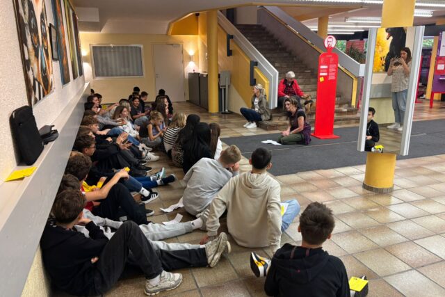 Schüler:innen sitzen am Boden und diskutieren